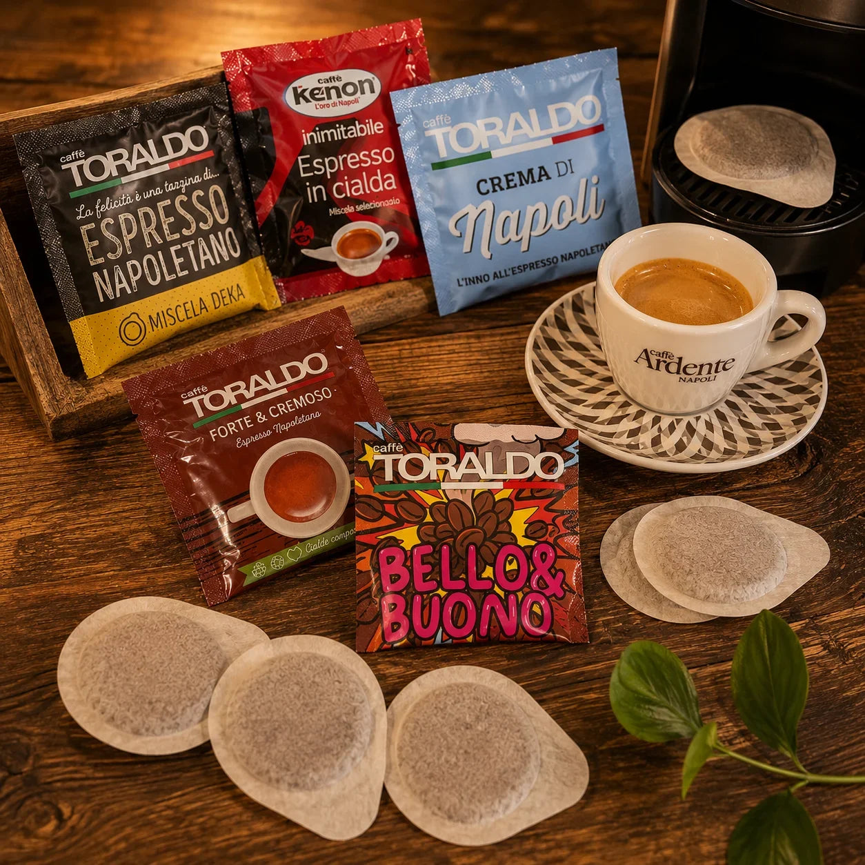Kaffepads Sortiment mit verschiedenen Verackungen und einzelnen Kaffeepads neben einer Tasse Espresso