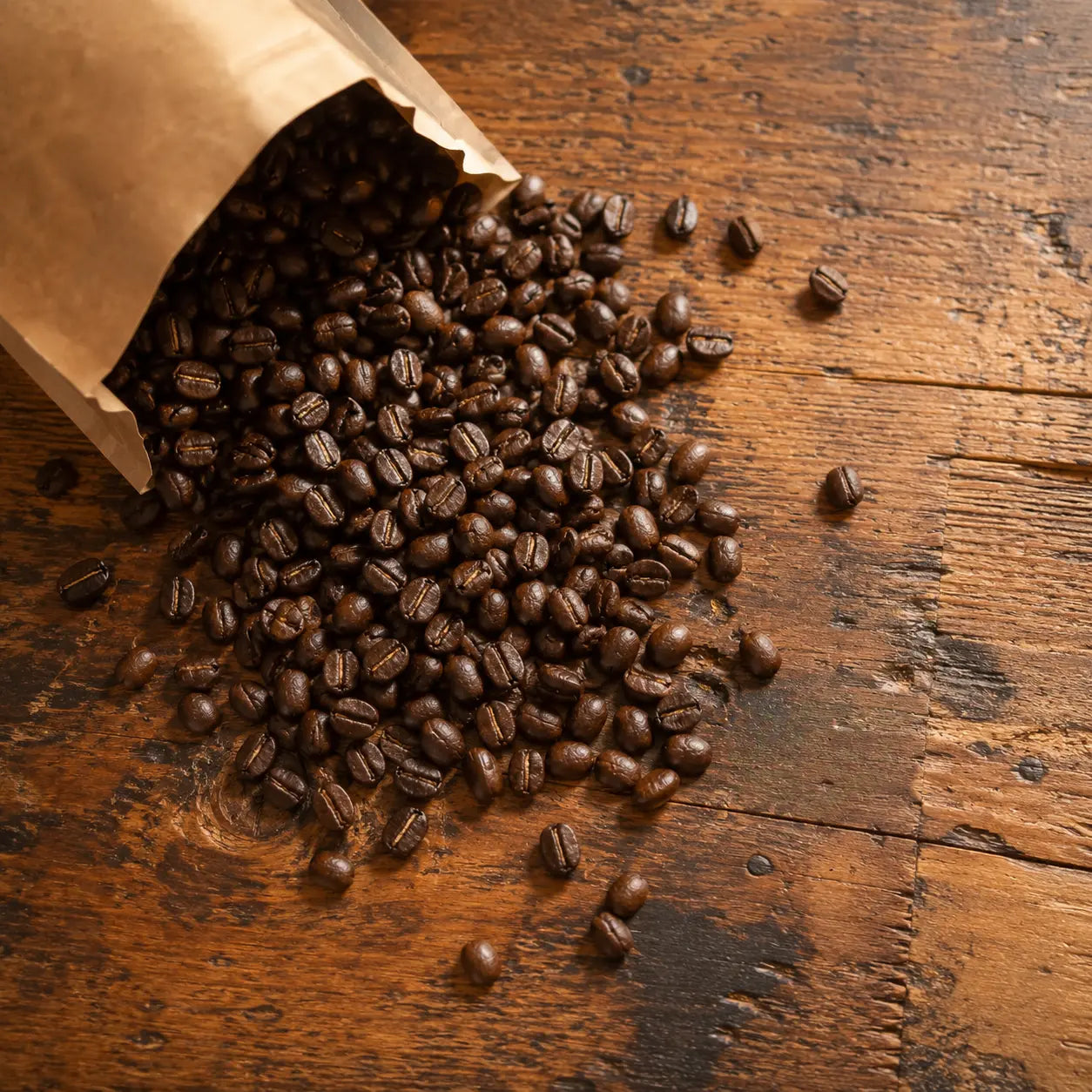 ganze Kaffeebohne, die aus einer Papiertüte herausfallen auf einem Holztisch