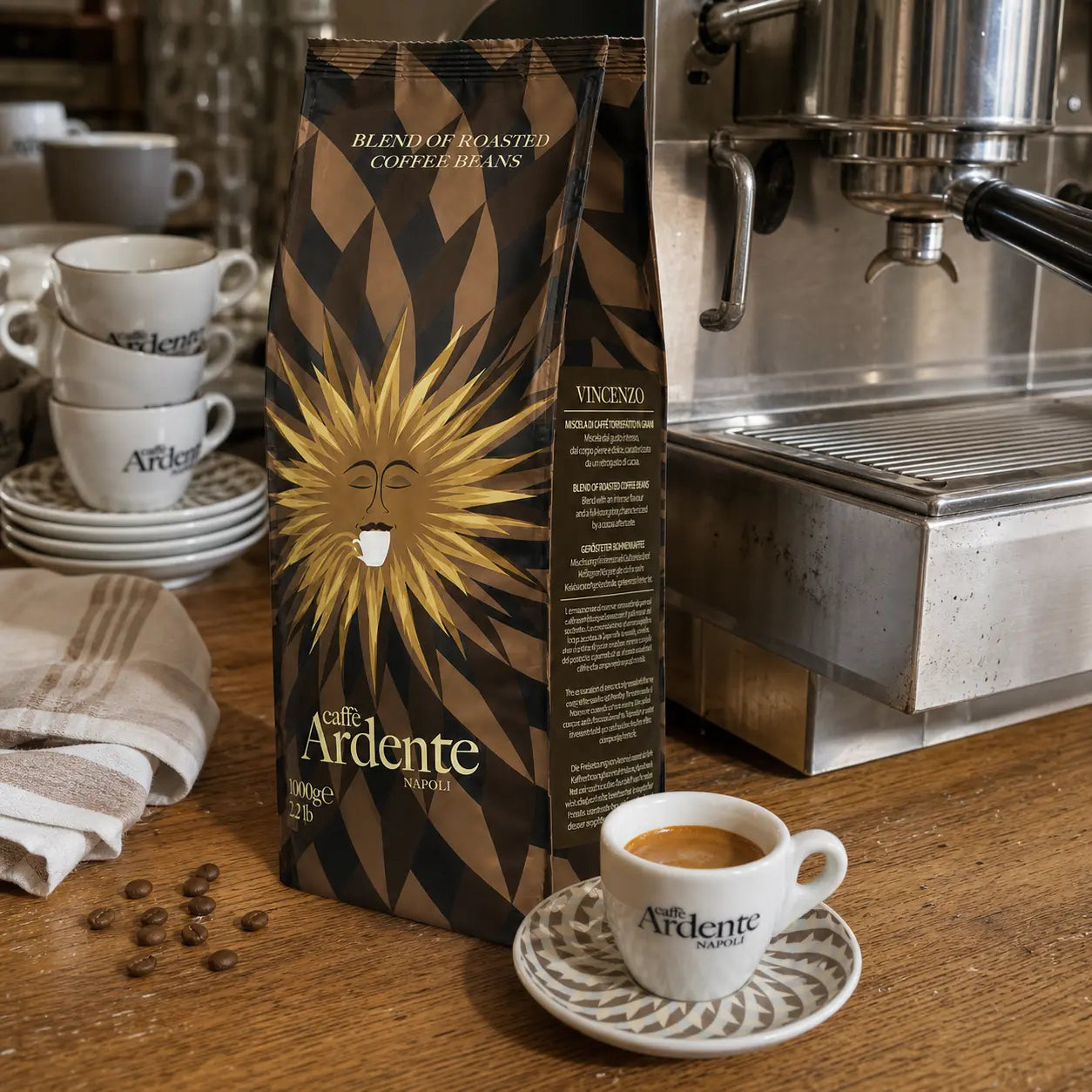 Caffè Ardente Vincenzo, 1000g Kaffeebohnen in dunkelbrauner Sonnenmotiv-Verpackung, mit Espressotasse an der Siebträgermaschine