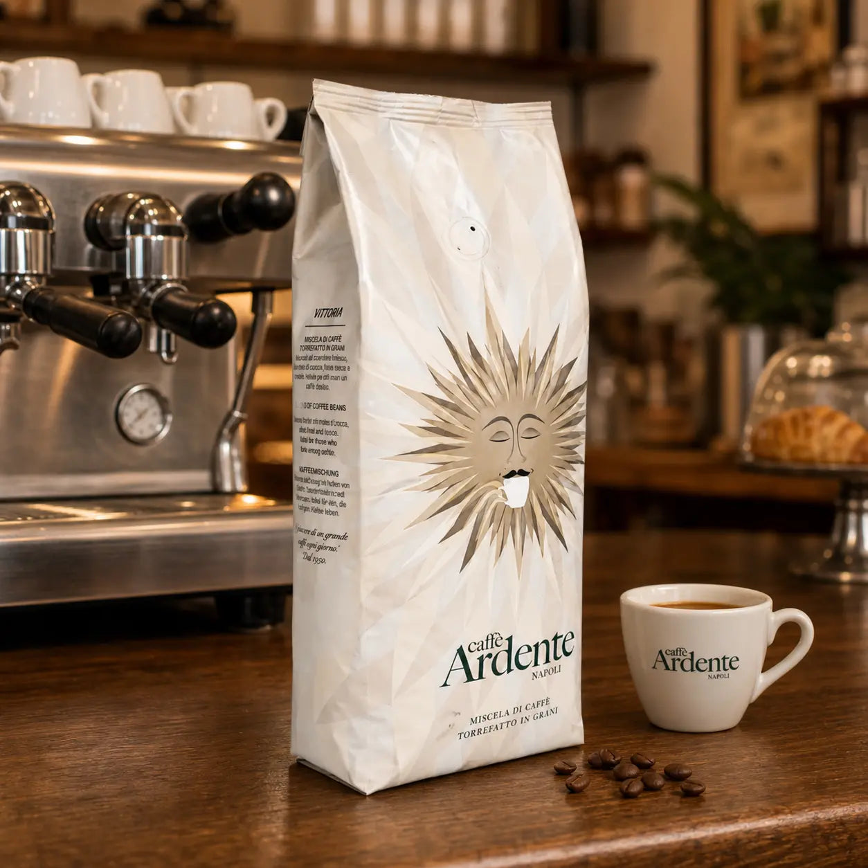 Caffè Ardente Vittoria Kaffeebohnen in cremeweißer Sonnenmotiv-Verpackung, mit Espressotasse auf Holztheke im Café