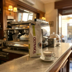 Caffè Toraldo Linea Verde, Kaffeebohnen mit Cappuccino auf Marmortheke vor der Siebträgermaschine im Café