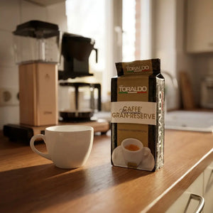 Caffè Toraldo Macinato Gran Reserve, Espresso Napoletano Verpackung neben Kaffeetasse auf Küchenarbeitsplatte