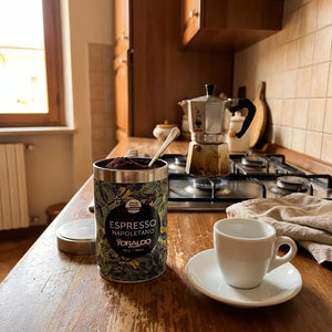 Caffè Toraldo Espresso Napoletano, 250g gemahlener Kaffee in Dose mit Löffel neben Espressotasse und Mokkakanne auf dem Herd