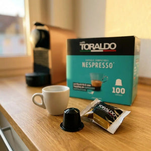 Caffè Toraldo Nespresso-kompatible Kapseln Gourmet, 100er-Packung mit Espressotasse und Kapsel auf Küchentheke
