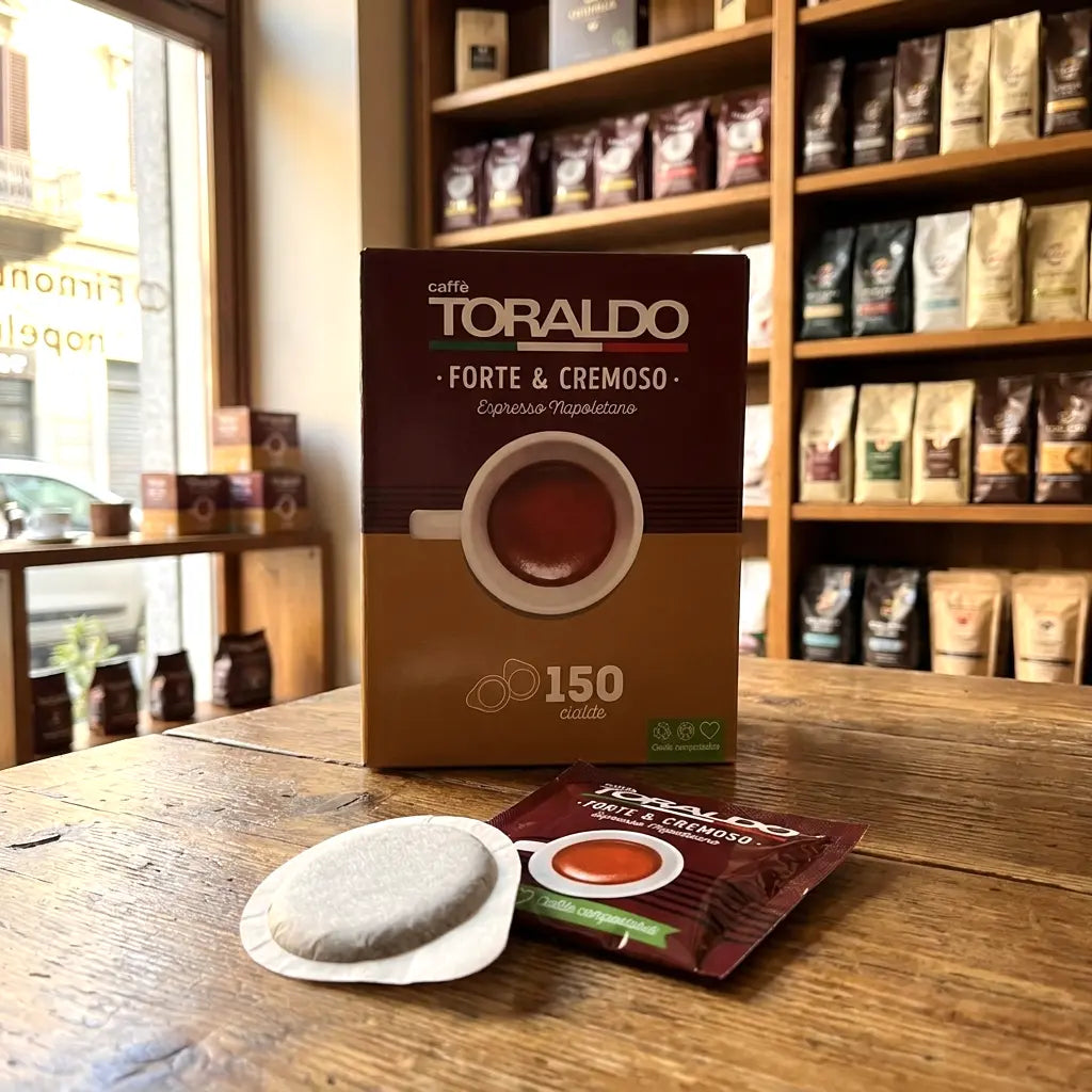 Caffè Toraldo Forte & Cremoso, 150 ESE-Pads-Packung mit einzelnem Pad-Beutel und Kaffeepad auf Holztisch im Ladengeschäft