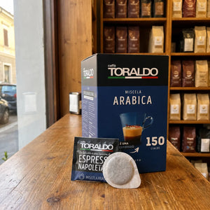 Caffè Toraldo Miscela Arabica, 150 ESE-Pads-Packung mit einzelnem Pad-Beutel und Kaffeepad auf Holztheke im Ladengeschäft